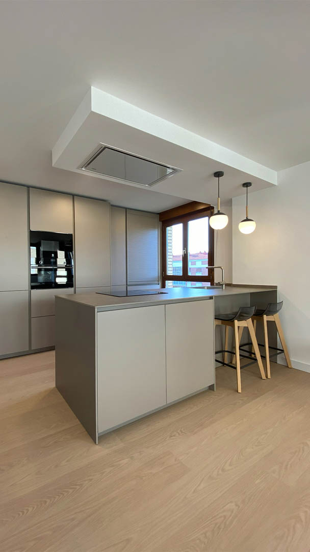 Cocina moderna en paralelo con península central, acabado satinado taupe y cajón técnico con iluminación LED integrada