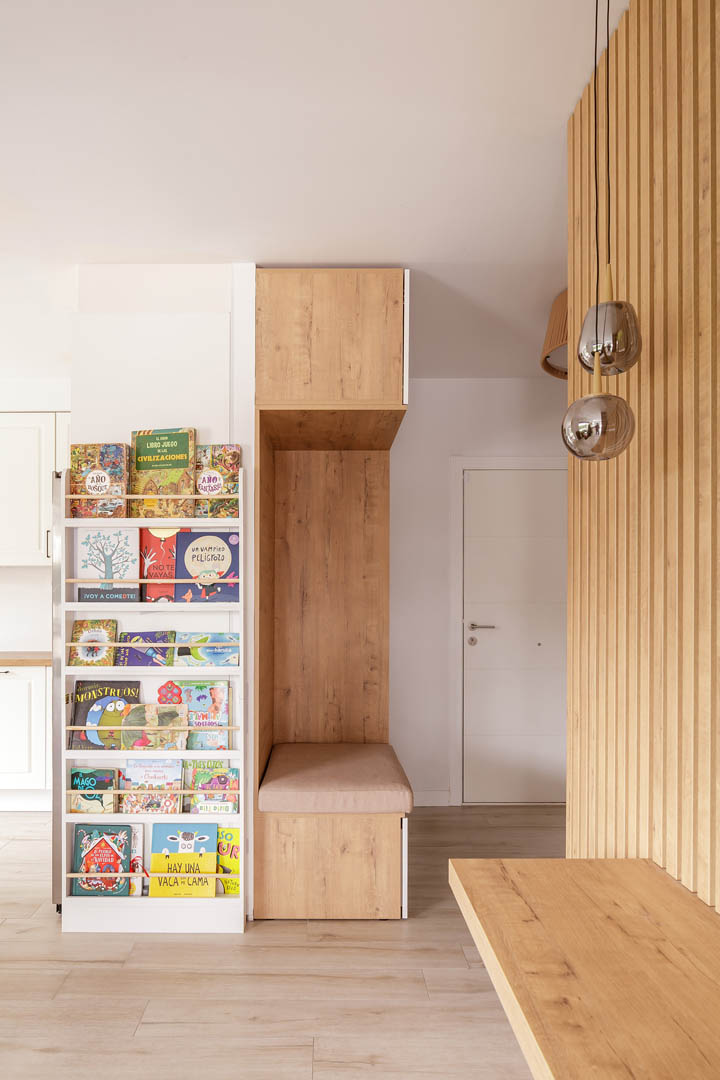 Detalle de revestimiento en palillería vertical de madera con espejo de media luna y balda integrada en zona de entrada