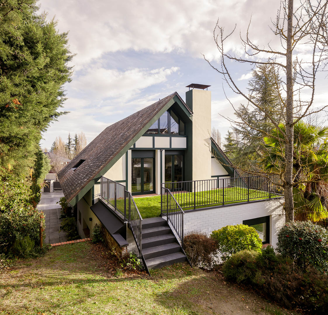 Vista exterior de vivienda reformada con carpintería PVC color verde musgo contrastando con fachada blanca