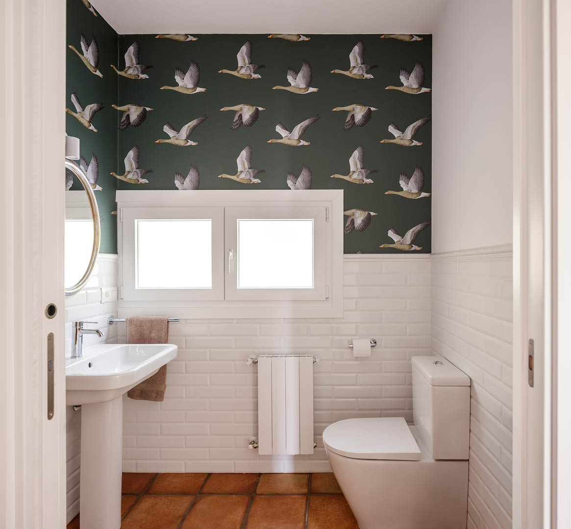 Bañera exenta con azulejo tipo metro a media altura y lámpara de araña decorativa en baño principal