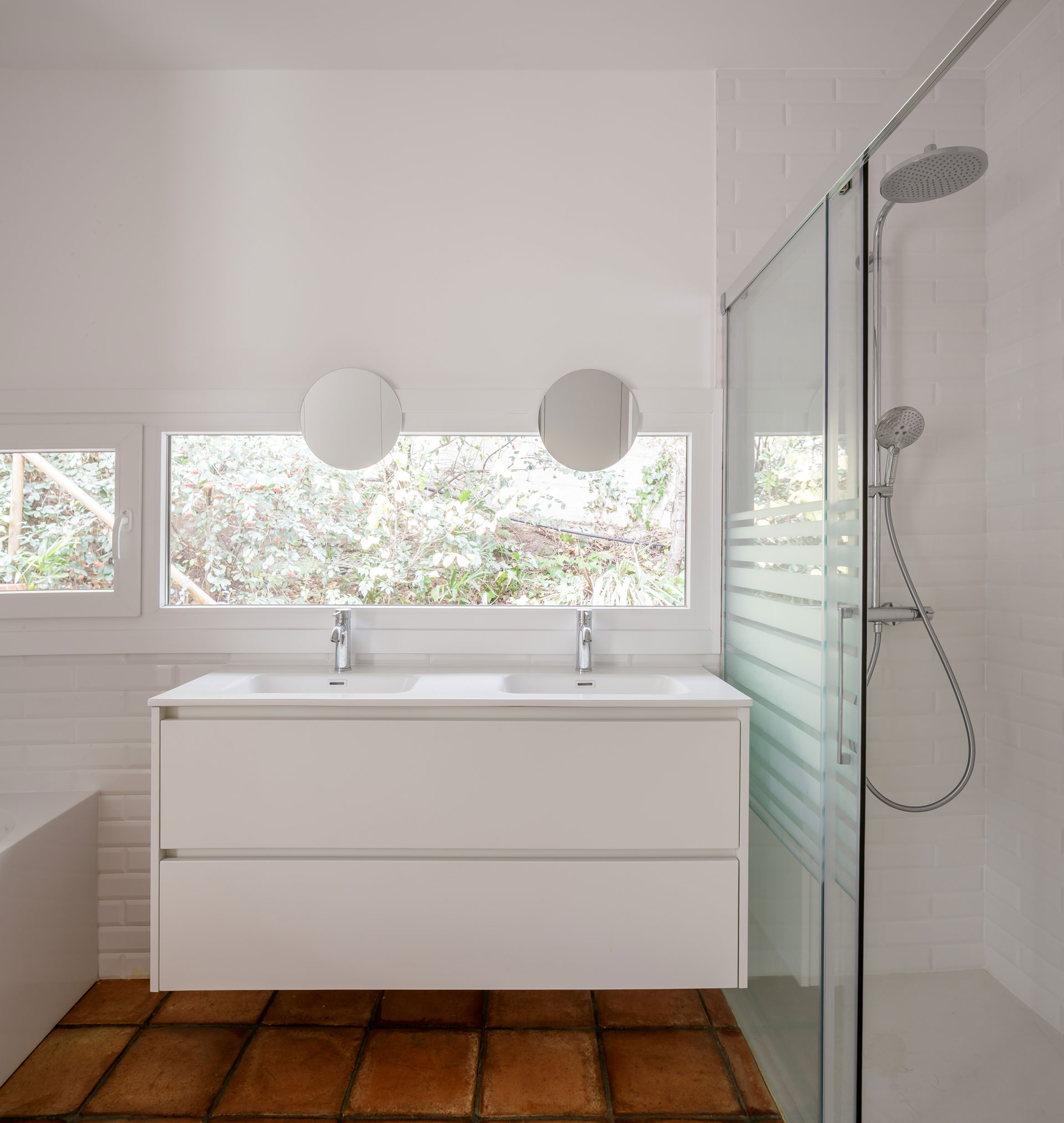 Baño de diseño con bañera exenta, azulejo tipo metro blanco y lámpara de araña decorativa