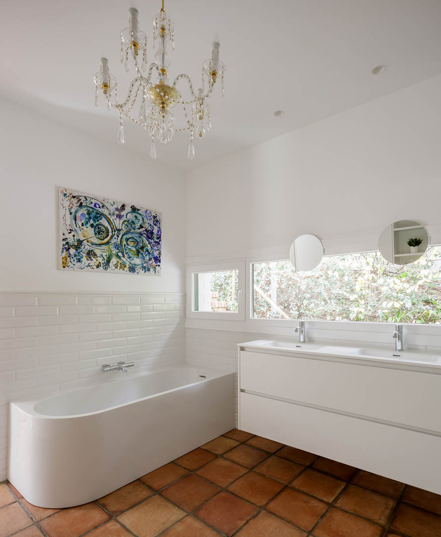 Vista completa de baño principal con bañera, mueble suspendido y continuidad visual con dormitorio