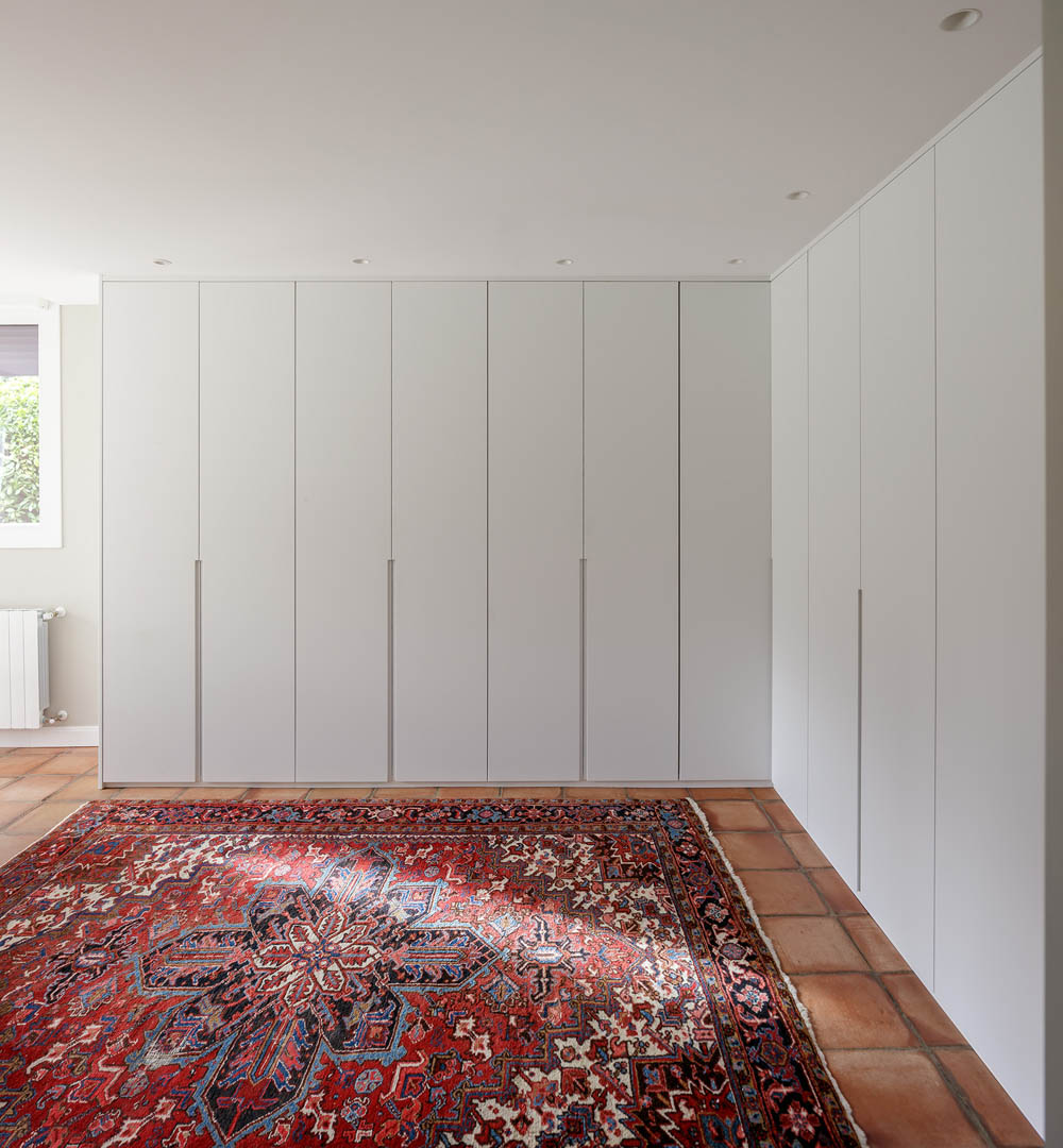 Detalle de armario empotrado con líneas depuradas y acabado lacado blanco reforzando amplitud espacial