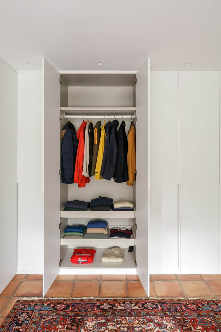 Vestidor con armario en L a medida, frentes lacados blancos y organización interior personalizada con barras y baldas