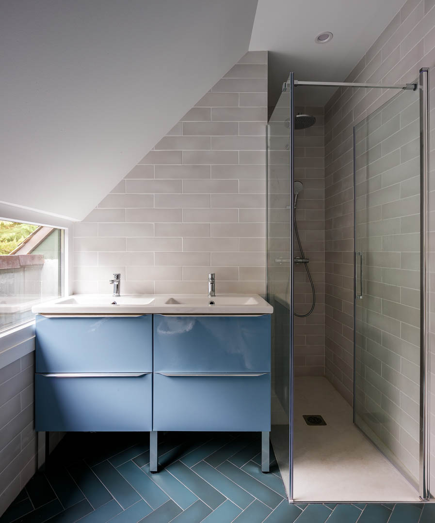 Baño principal amplio con mueble suspendido blanco, doble lavabo y espejos circulares frente a ventanal