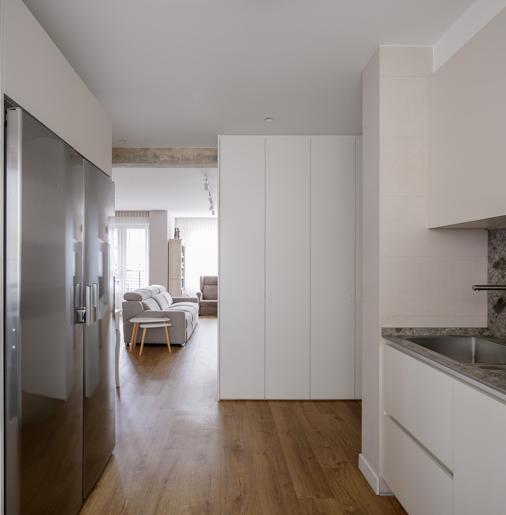 Armarios empotrados a medida OLLER 07 con frentes lacados en blanco mate, líneas depuradas y verticales, integrados discretamente en pasillo con arquitectura contemporánea