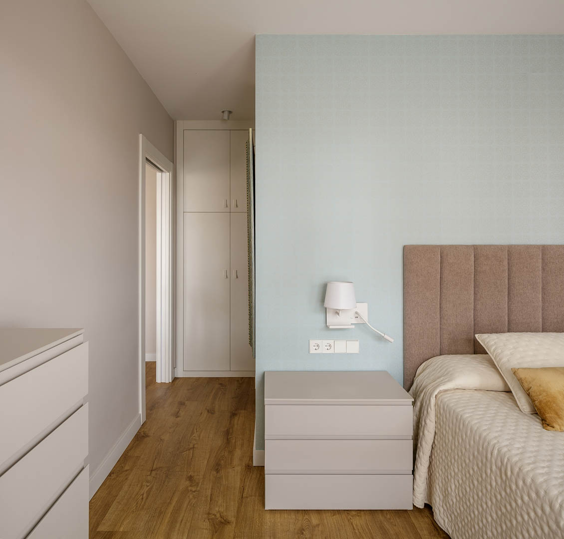 Detalle de armario empotrado a medida con líneas depuradas verticales, acabado lacado blanco mate, reforzando sensación de amplitud y limpieza espacial en corredor