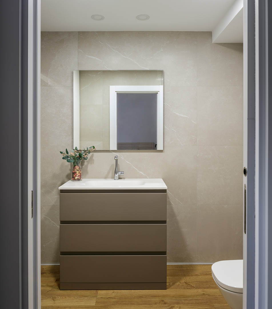 Baño principal OLLER 07 Vitoria con mueble suspendido blanco de doble lavabo, espejos circulares redondos, ventanal con luz natural y diseño contemporáneo minimalista