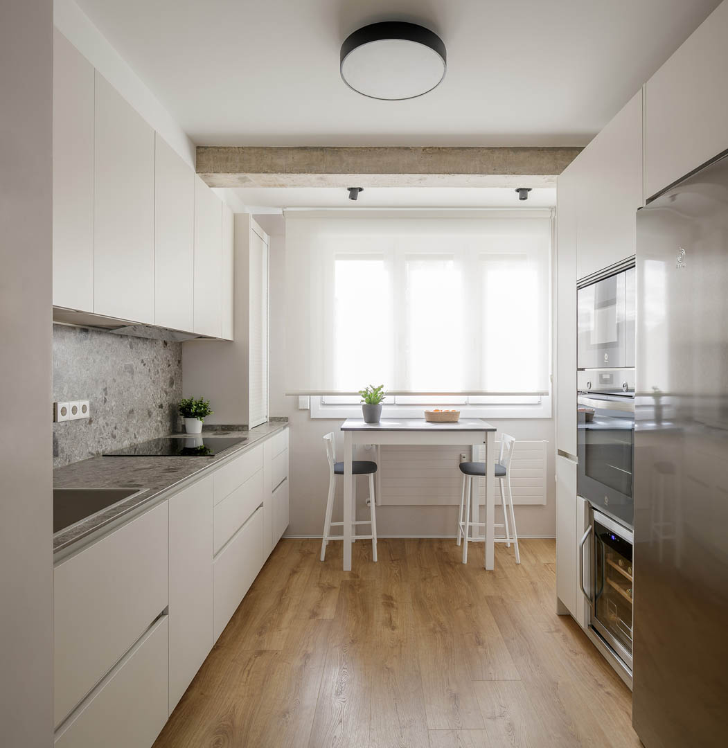 Cocina moderna con renovación funcional, materiales neutros luminosos, iluminación integrada LED y distribución optimizada para uso cotidiano en vivienda OLLER 07