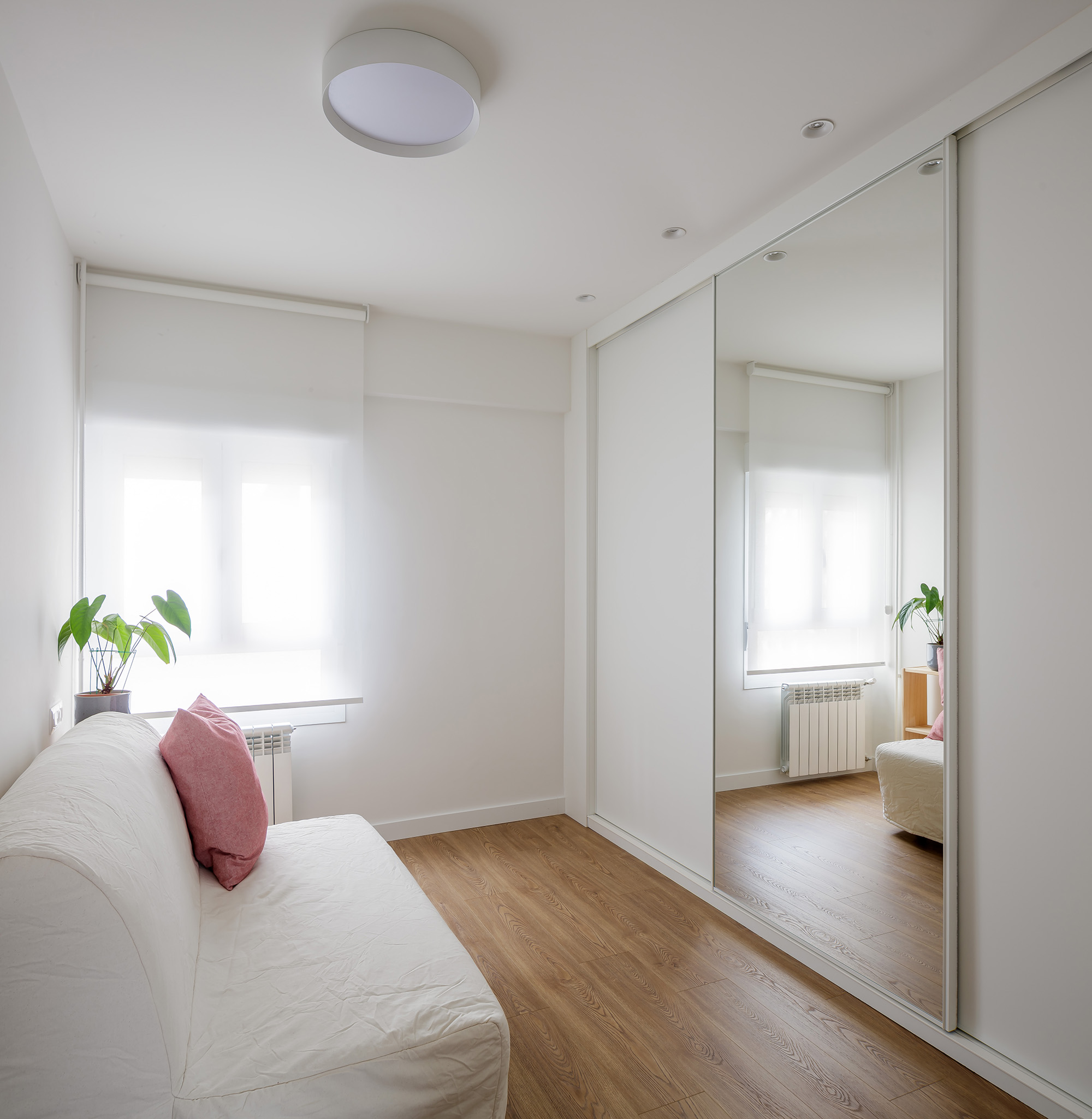 Armarios empotrados a medida OLLER 08 con frentes lacados en blanco mate, líneas depuradas y verticales, integrados discretamente en pasillo con arquitectura contemporánea