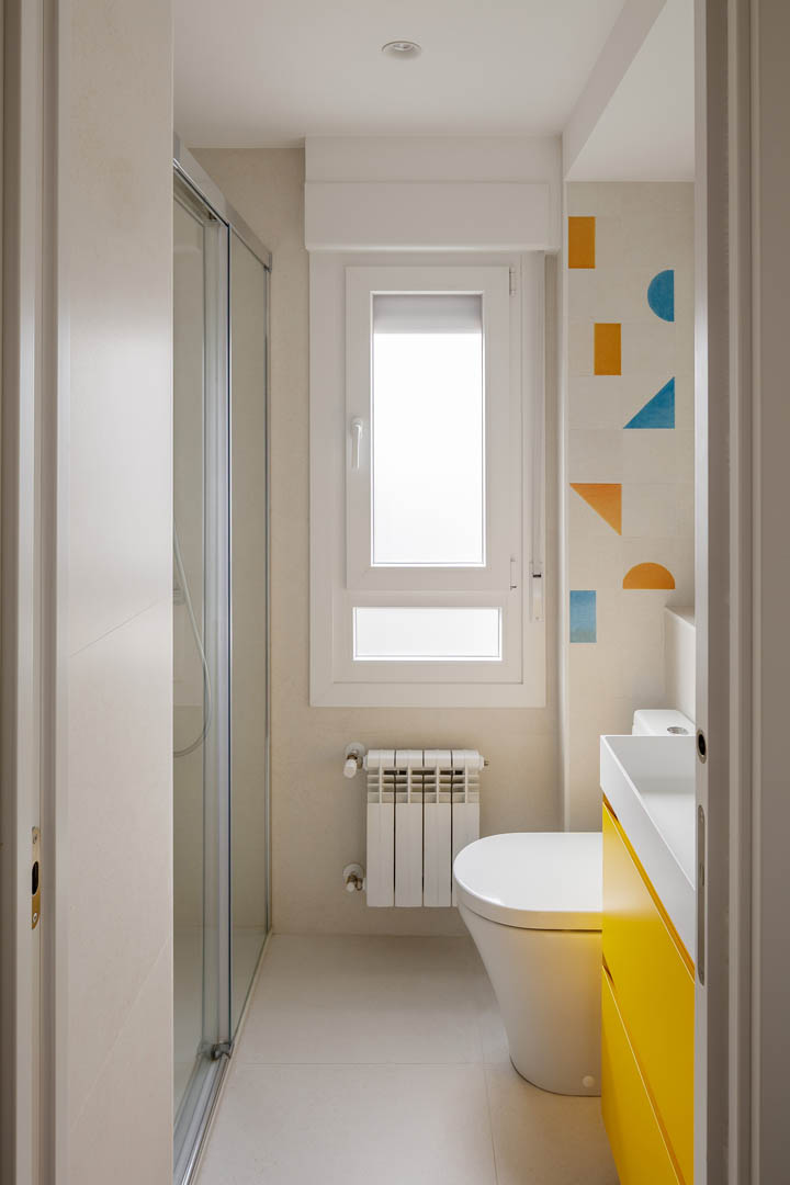 Baño principal amplio OLLER 08 con mueble suspendido blanco minimalista de doble lavabo, espejos circulares modernos y ventanal panorámico con luz natural en reforma Vitoria