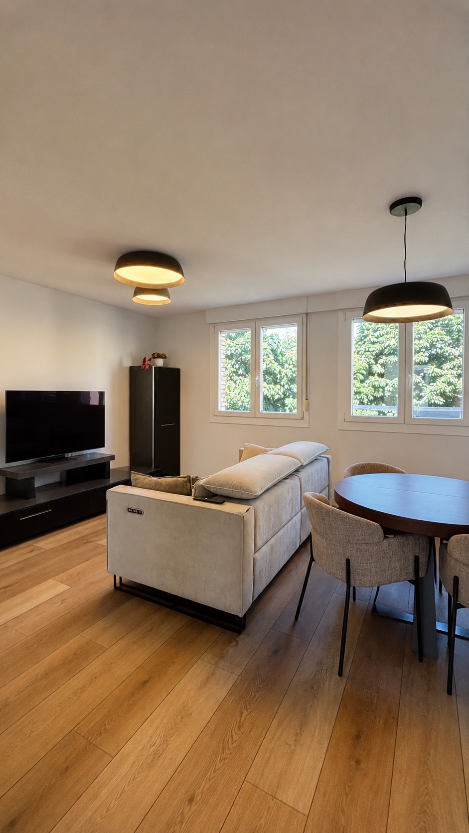 Salón reformado OLLER 09 con mueble de televisión, sofá tapizado en tono claro, comedor y pavimento vinílico continuo en toda la vivienda